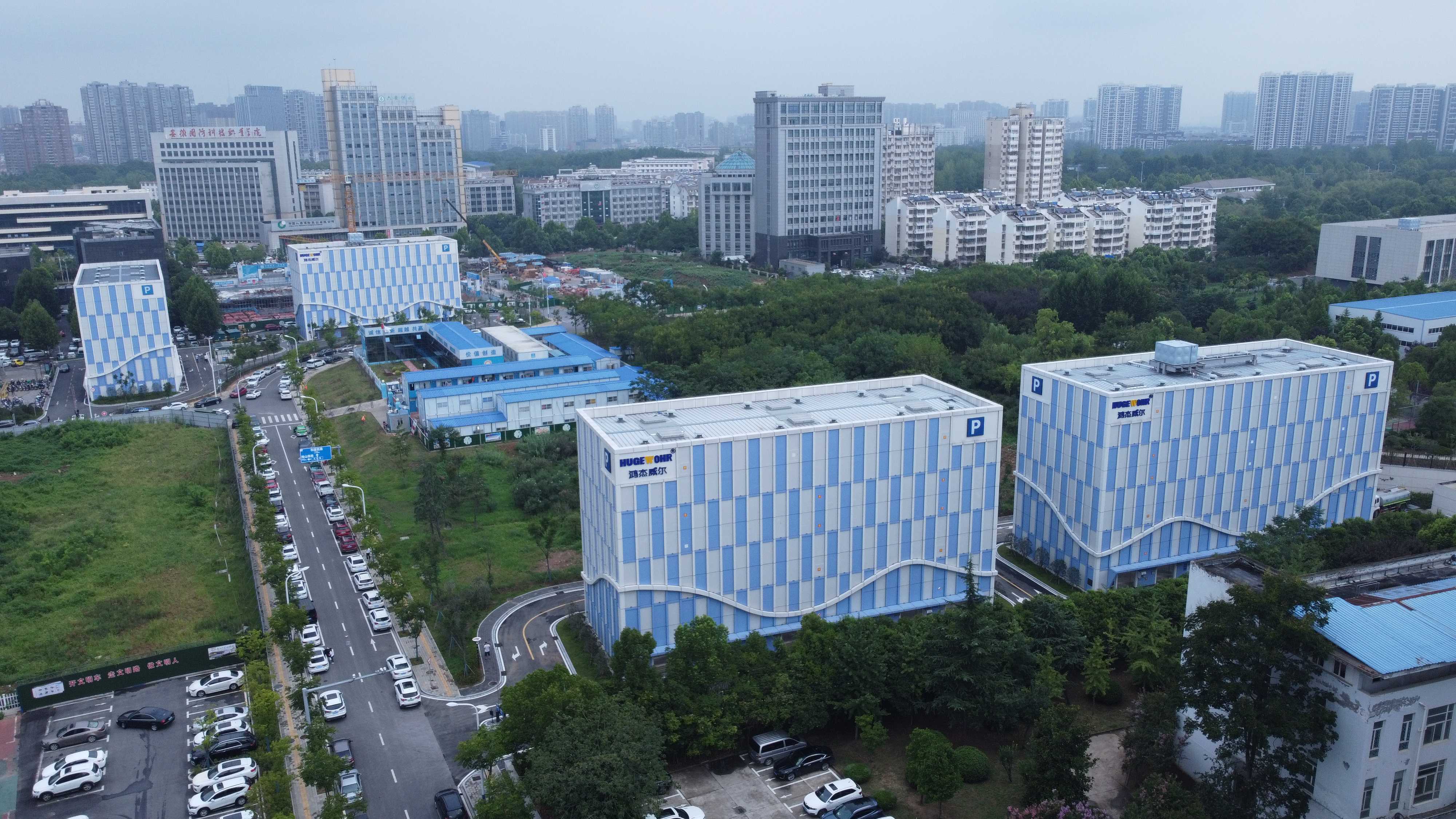 现代化住宅小区建筑群,多层楼房排列整齐,白色墙面配深色屋顶,绿化景观优美,阳光明媚